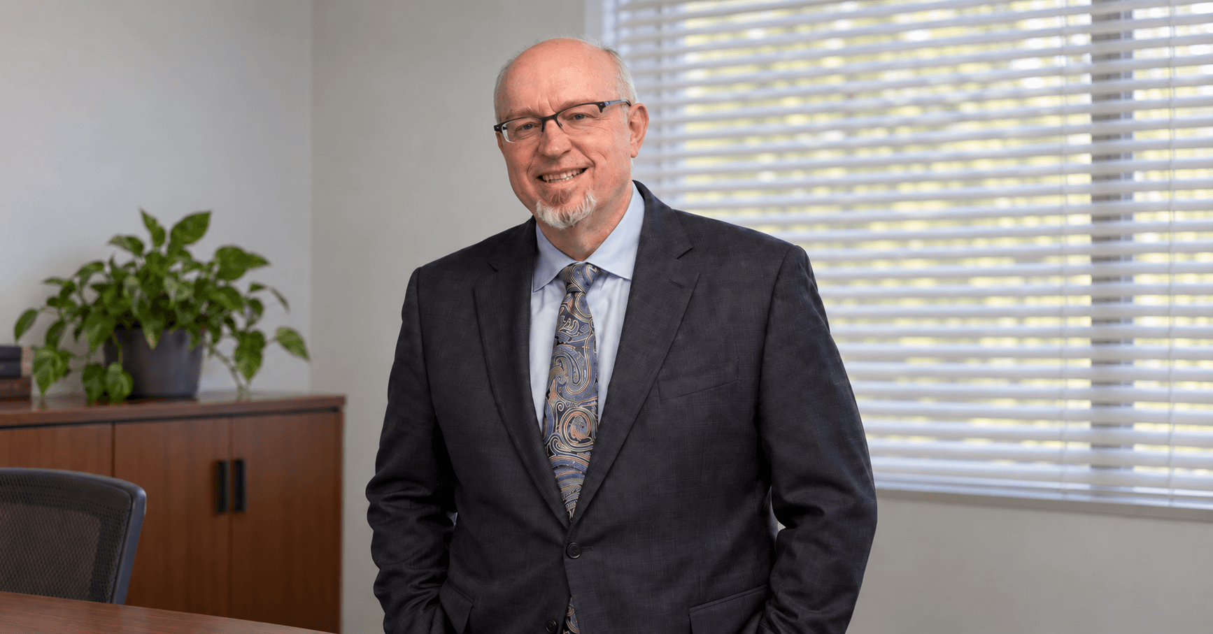 Attorney in a suit standing beside an office window